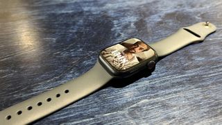 En Apple Watch 8 ligger utsträckt på ett mörkt träbord.