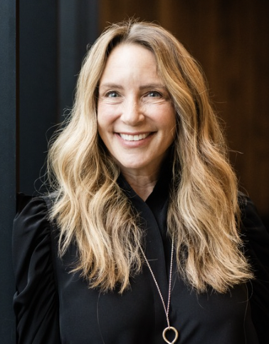 A headshot of a woman with blonde hair smiling at the camera