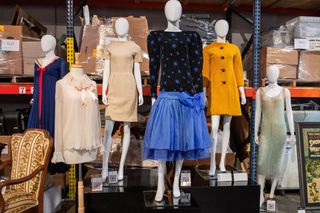 Princess Diana's dresses and pink blouse on mannequins in a warehouse