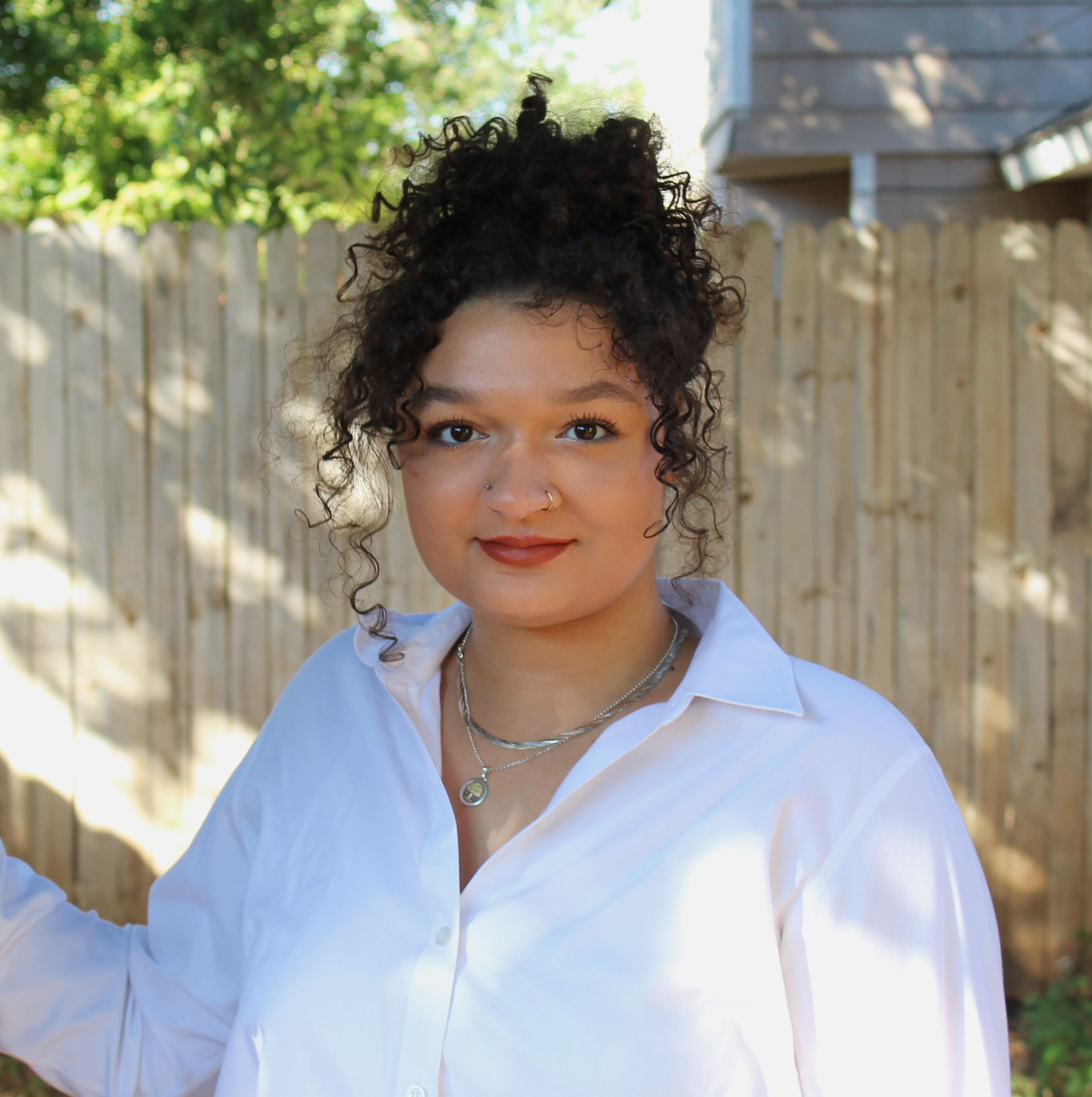 headshot of plant expert sydni d'amico, wearing a white shirt with curly brunette hair