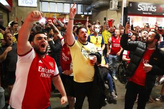 Arsenal football fans / supporters on the concourse inside a stadium drinking alcohol