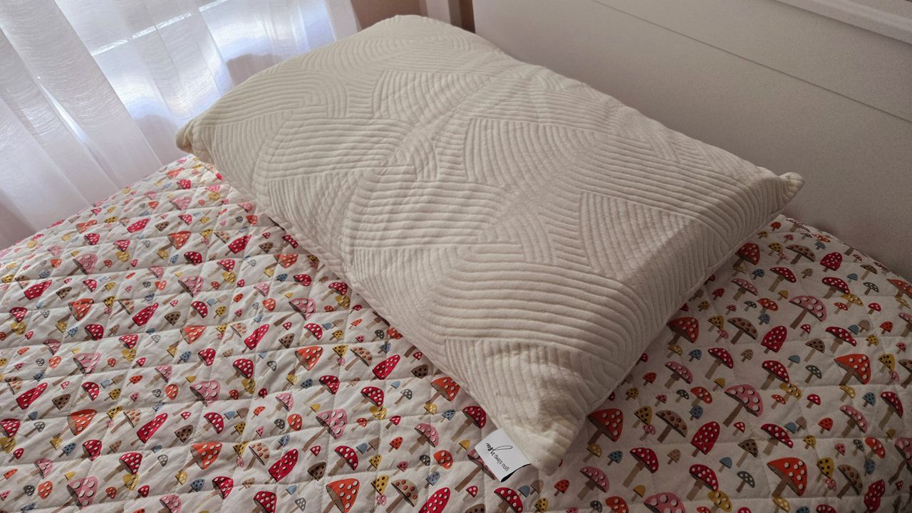 Coop Sleep Goods Adjustable Latex Pillow on our reviewer's colorful bed. It was just unboxed at this point so it's wrinkly and flat.