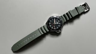 The Hamilton Khaki Navy Frogman with a black dial and a green rubber strap on a grey background