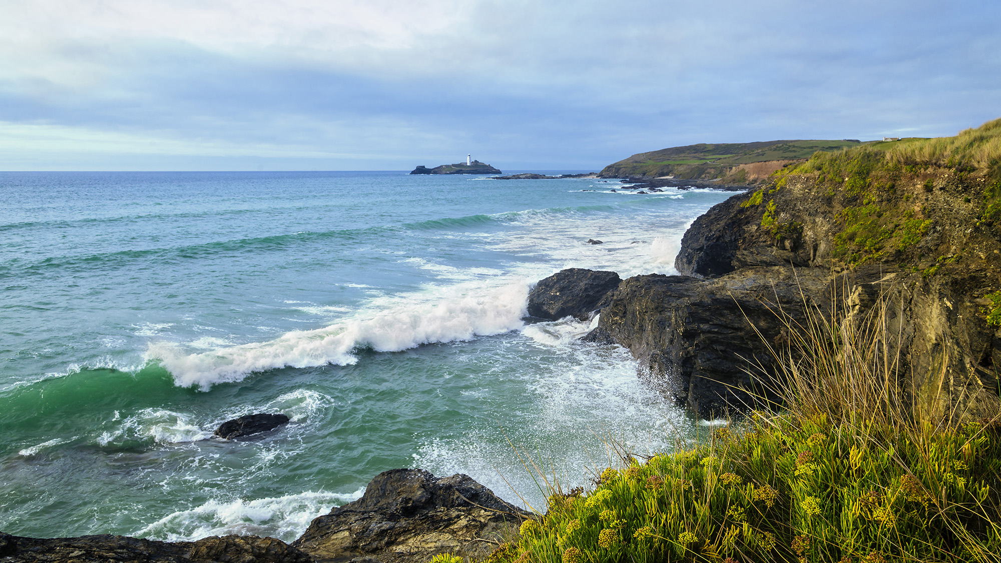 Coastlines with pounding surf and a lighthouse in the distance