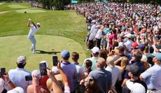 Scottie Scheffler strikes a tee shot in front of a large crowd