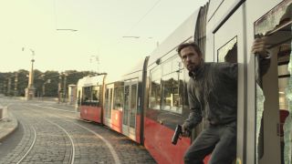 Ryan Gosling leans out of a train with a gun in hand in The Gray Man.