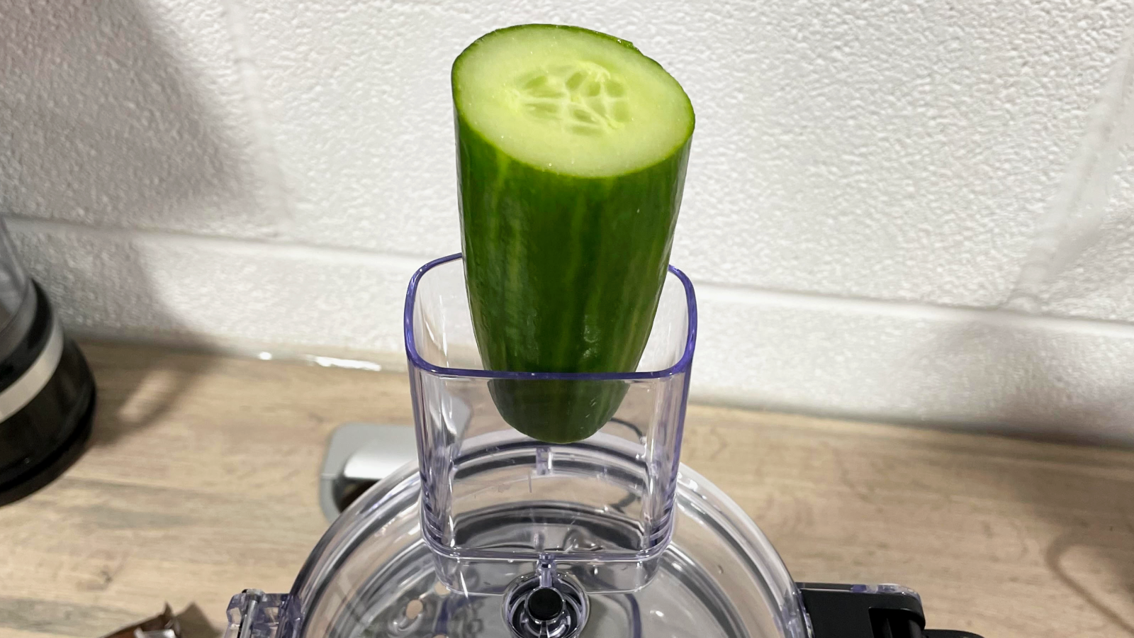 A closeup of the KitchenAid 7 cup food processor feed tube, showing that a larger-diameter cucumber is too large to fit inside.