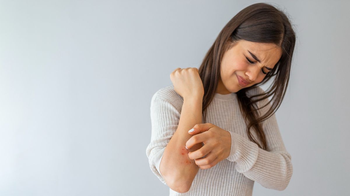 Woman scratching an itch on her arm.