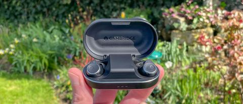 Cambridge Audio Melomania M100 in charging case held in hand in a yard