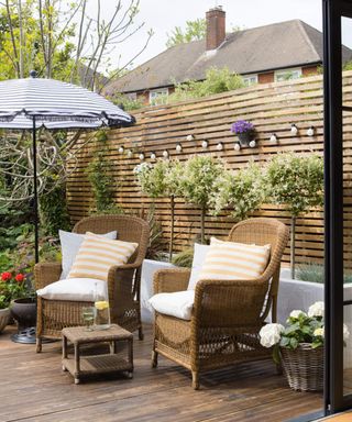 A backyard area with decked surface and two garden chairs