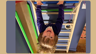 Image of a toddler hanging upside down from a wall climber