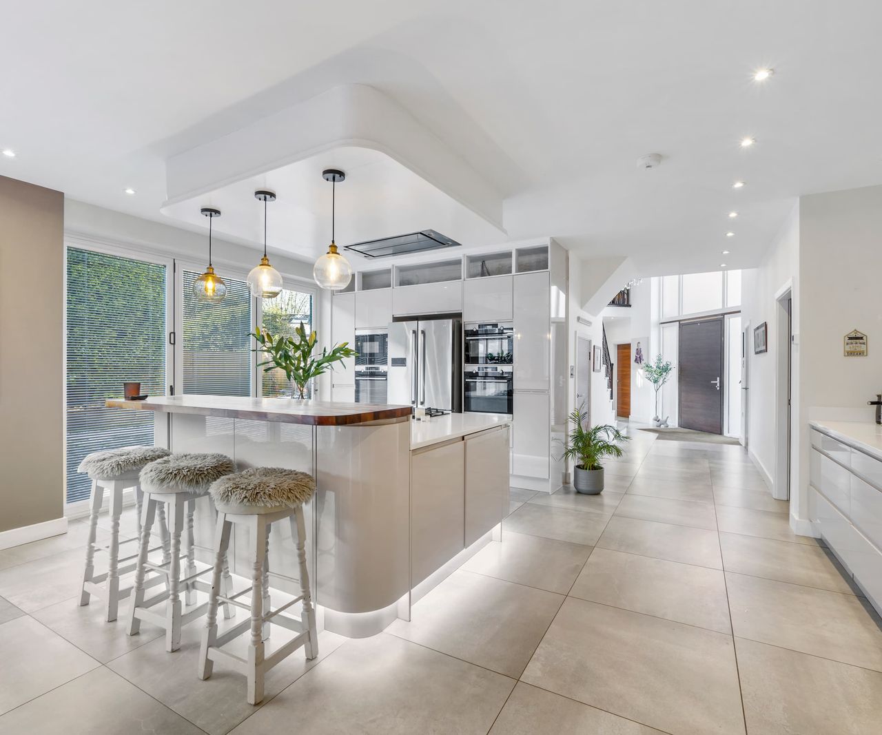 An open plan kitchen with overhead lights and a kitchen island in the middle of the room