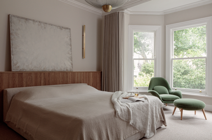 Neutral coloured bedroom with curtains and green chair