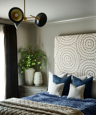 neutral bedroom with high upholstered headboard and bed with layered bedding