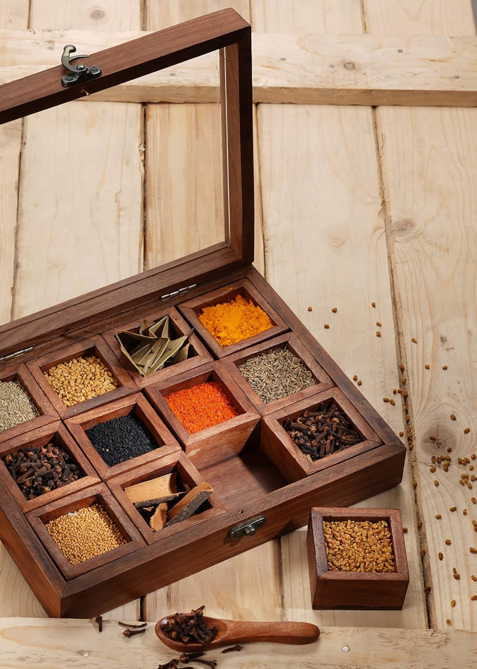 A wooden spice box with a spoon and different spices