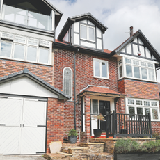 A large red brick home with a garage with white doors attached to the side.