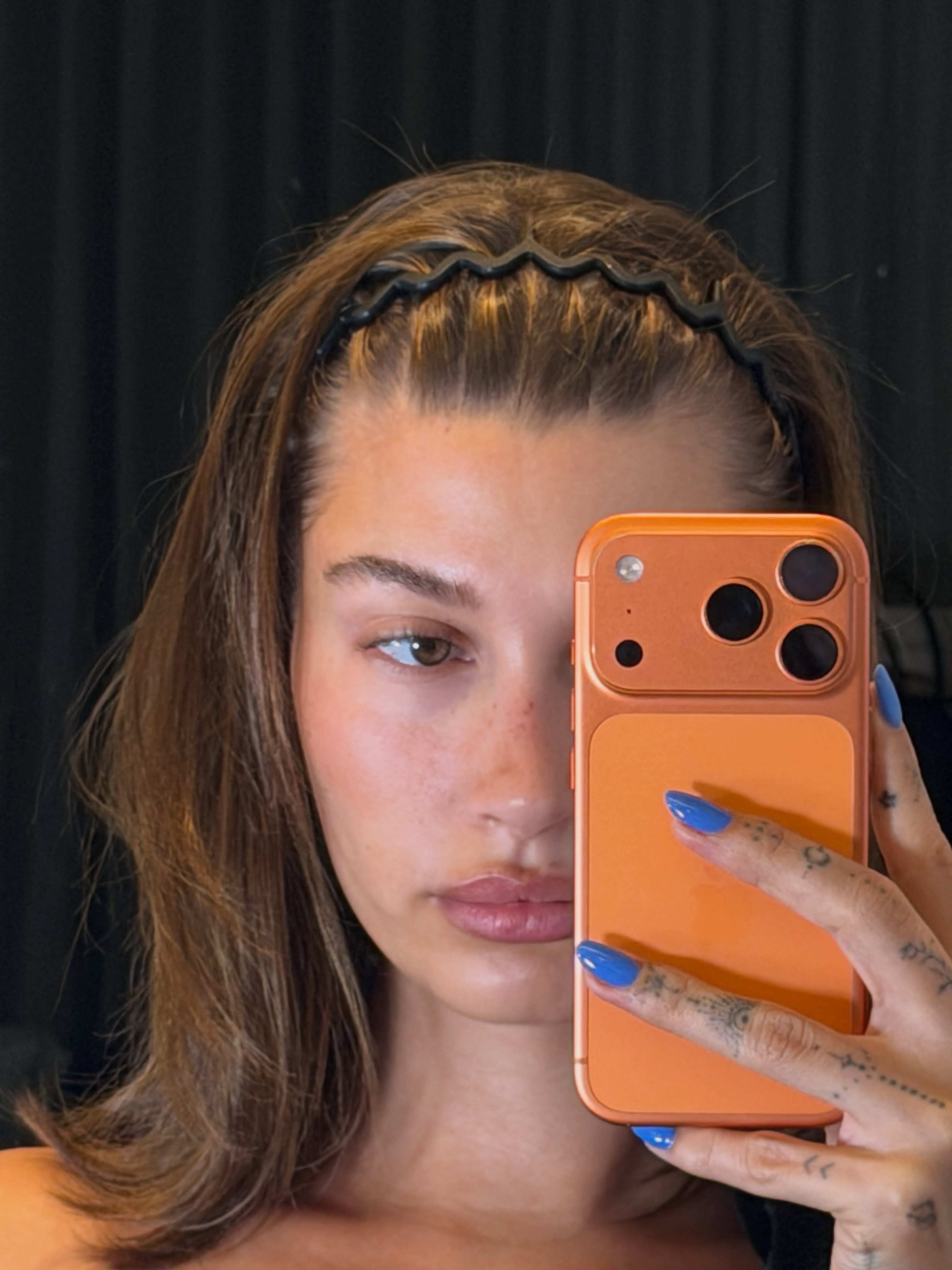 Glossy cobalt blue almond nails shown in a close-up mirror selfie of hailey bieber