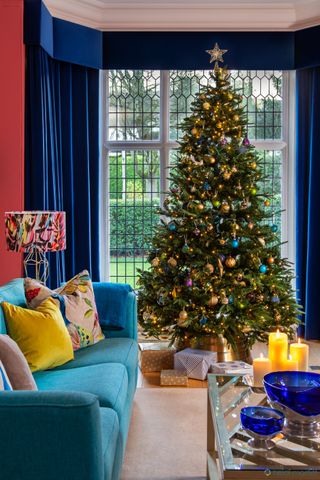 Christmas tree with blue and gold decor inn blue living room