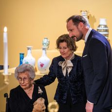 King Harald and Queen Sonja standing with Princess Astrid in a wheelchair