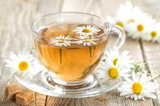 Glass Tea Cup Full Of Chamomile Tea And Flowers