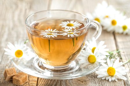 Glass Tea Cup Full Of Chamomile Tea And Flowers