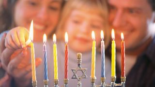 Here we see a family (woman, child and man) lighting a Menorah together (a sacred candelabrum with eight branches). 