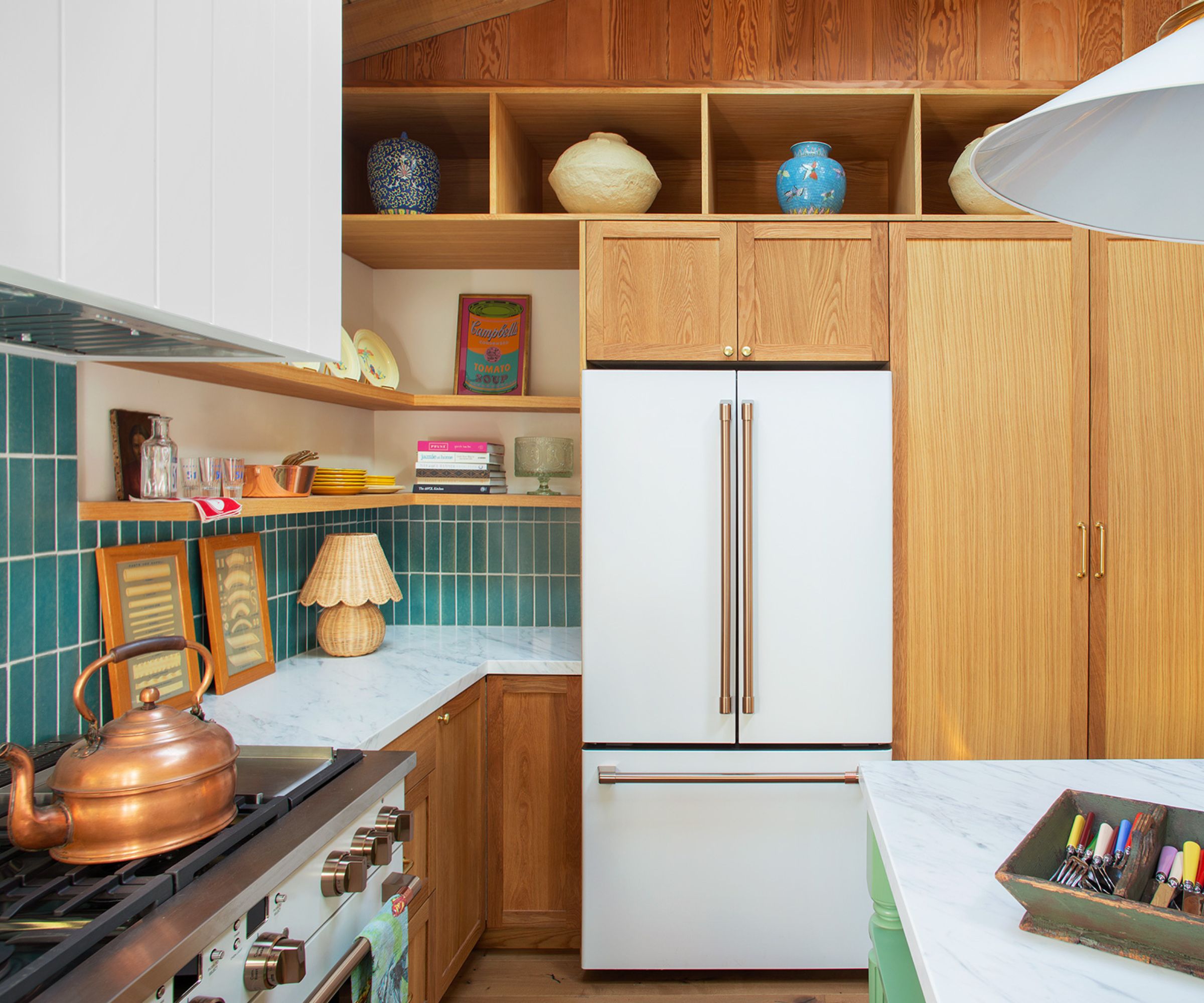 The corner of a wooden kitchen with blue backsplash tiles and marble countertops