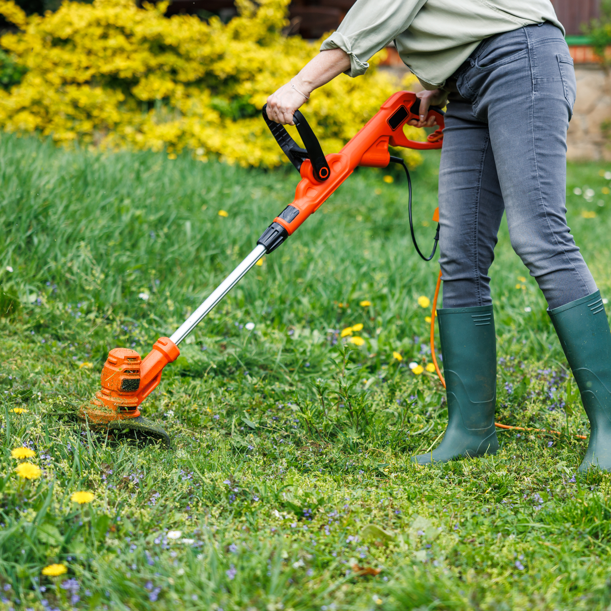woman using string trimmer in yard