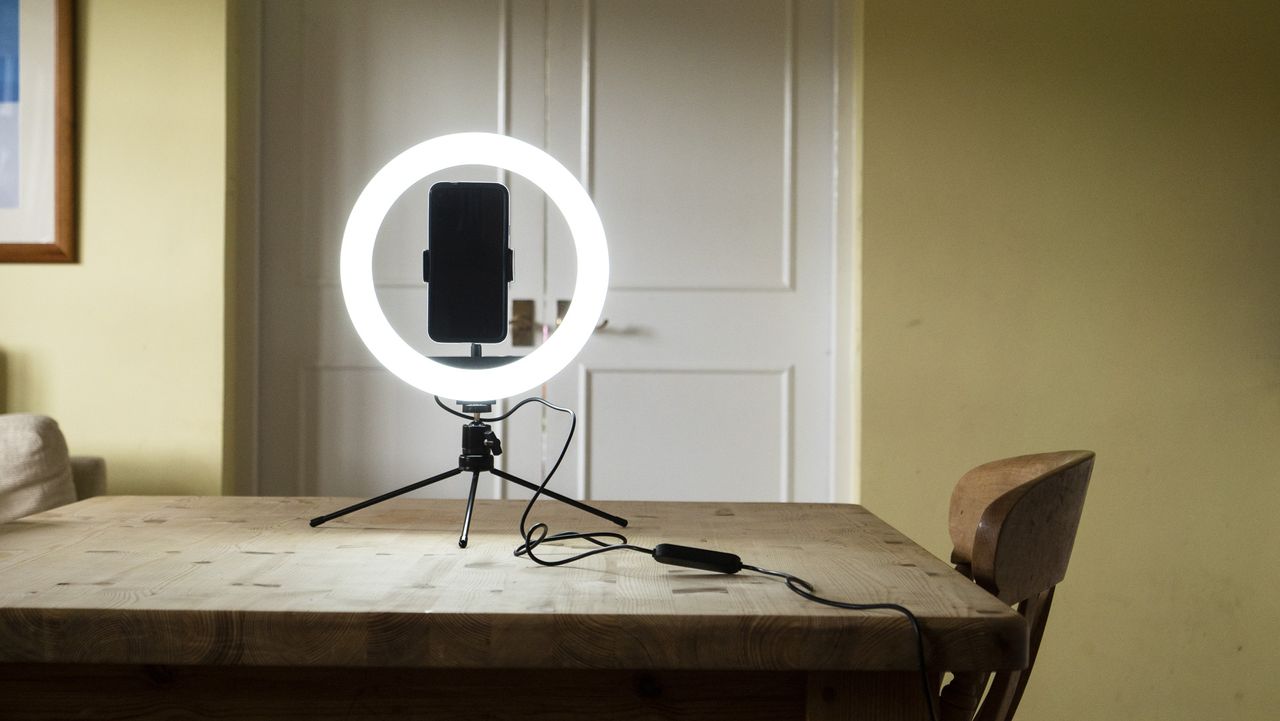 right light for phone switched on, placed on a wooden table with phone attached