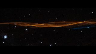 an orange ribbon of plasma stretches across the center of a starry view.