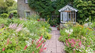 cottage garden plants in front of pretty cottage