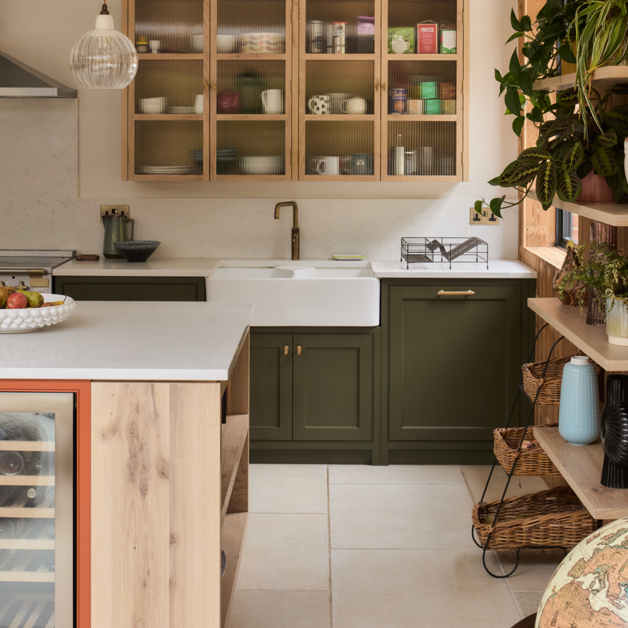 dark green and terracotta kitchen with wood panelling, white work tops, glazed wall unit, open shelving, white floor tiles