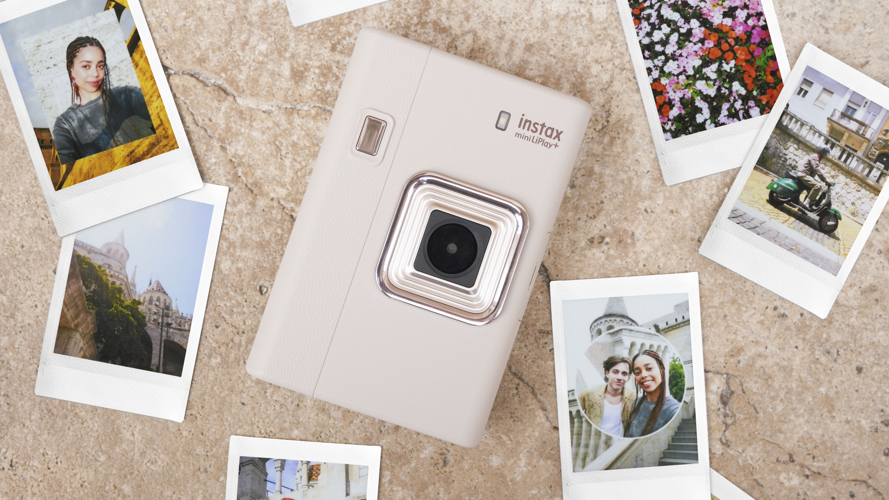 Fujifilm Instax mini LiPlay+ hybrid instant camera on a marble surface surrounded by instant prints