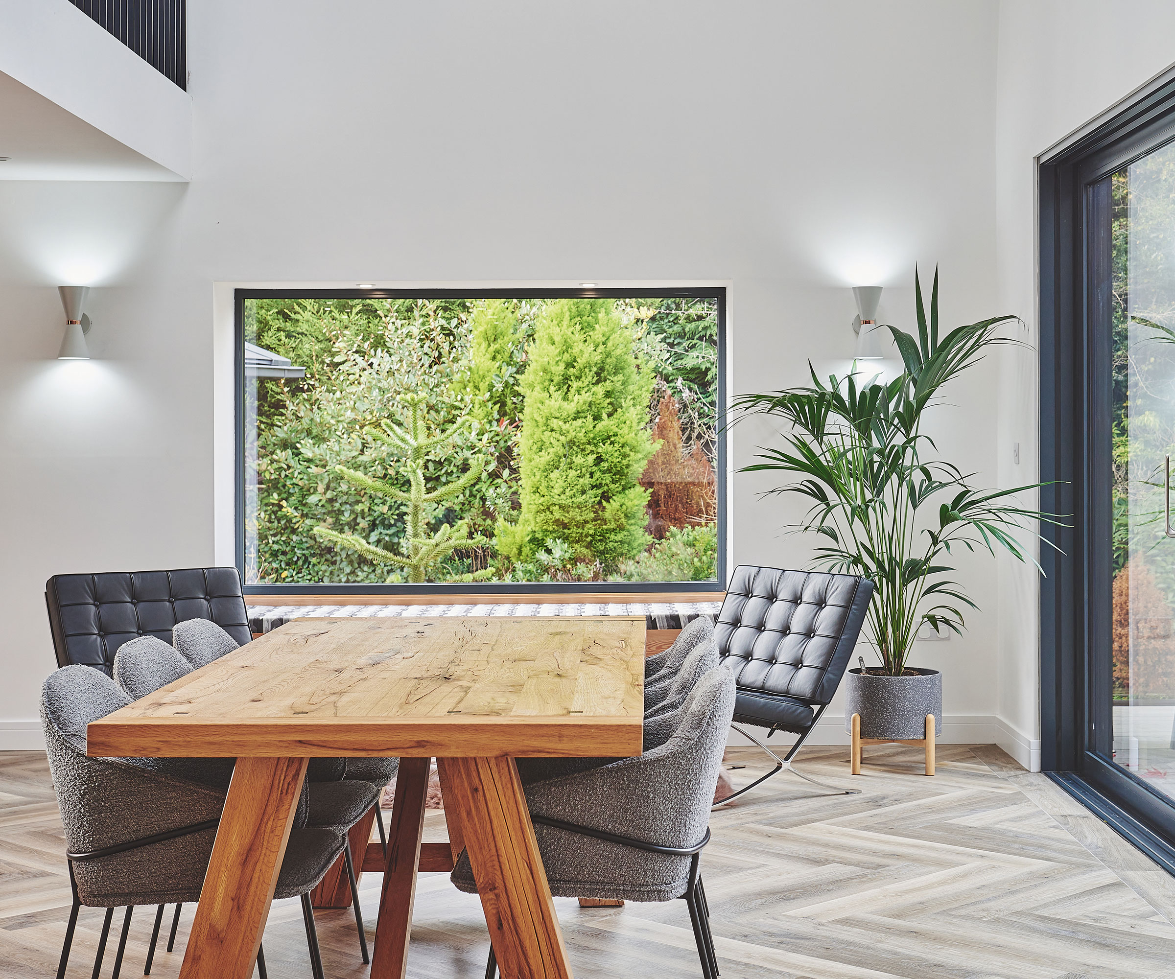 dining space in a modern home with a large picture window and sliding doors overlooking the garden