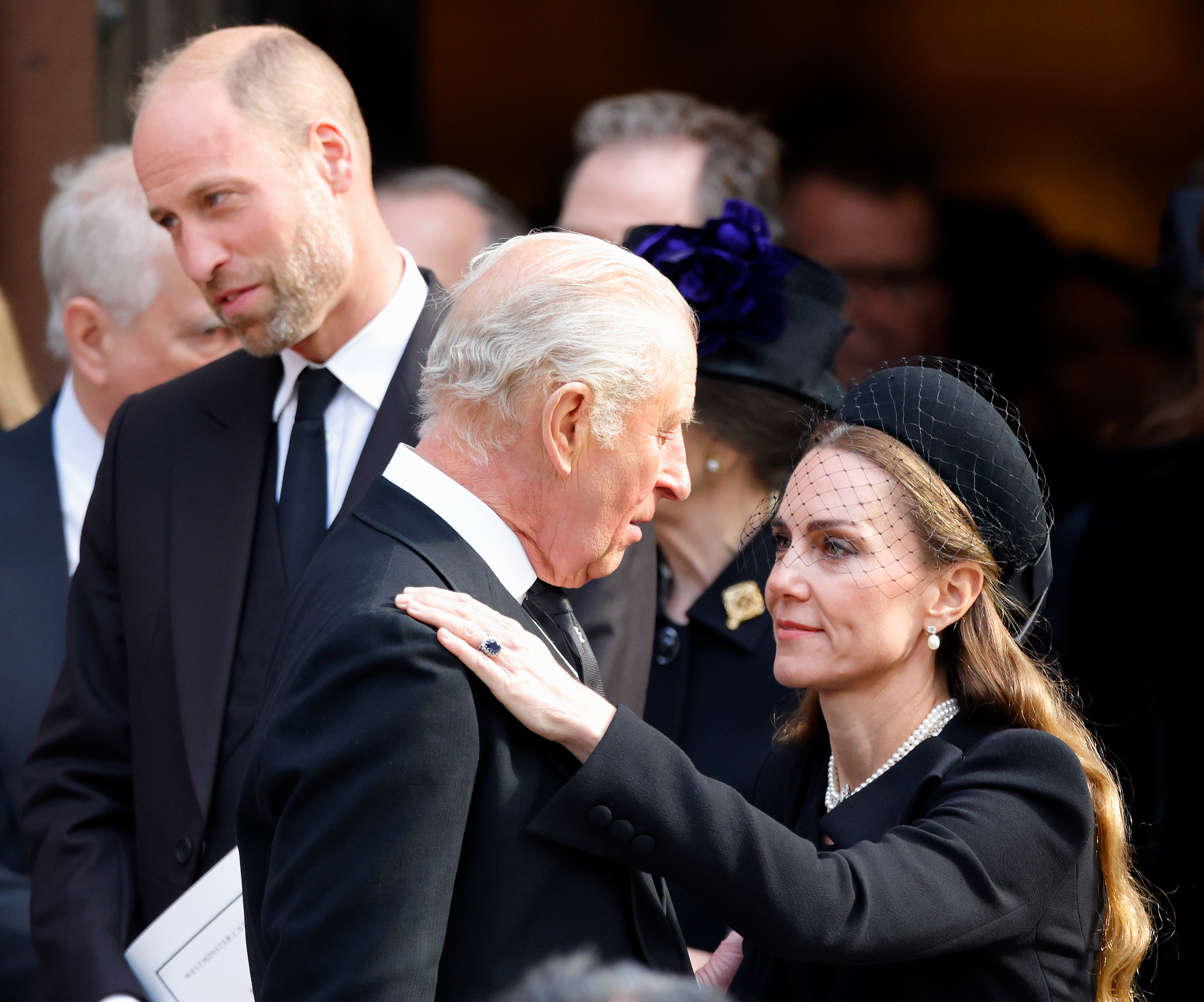 Princess Kate hugging King Charles with Prince William standing behind them