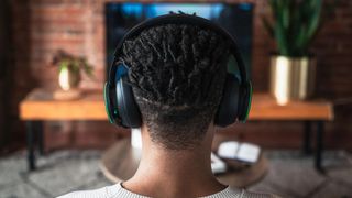 Back of a man's head wearing an Xbox wireless headset in his living room