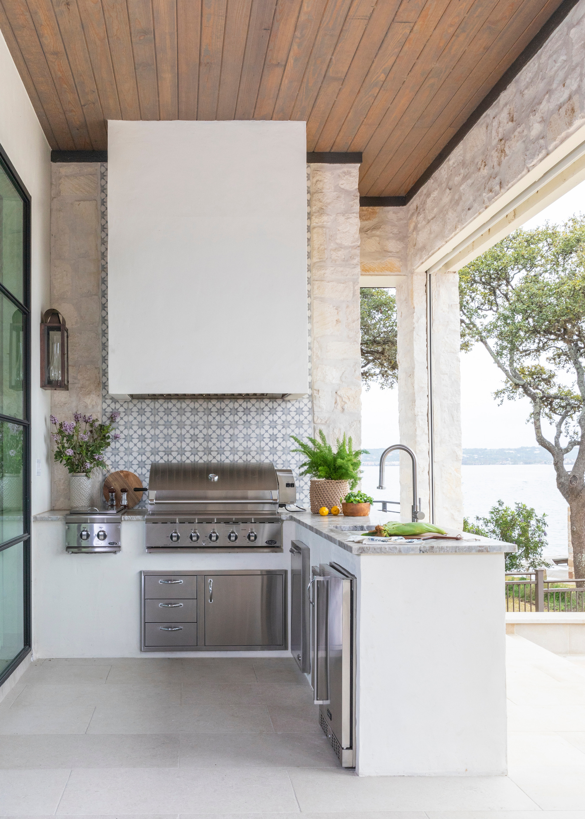L-shaped white outdoor kitchen with tiled splashback by Marie Flanih=gan Interiors