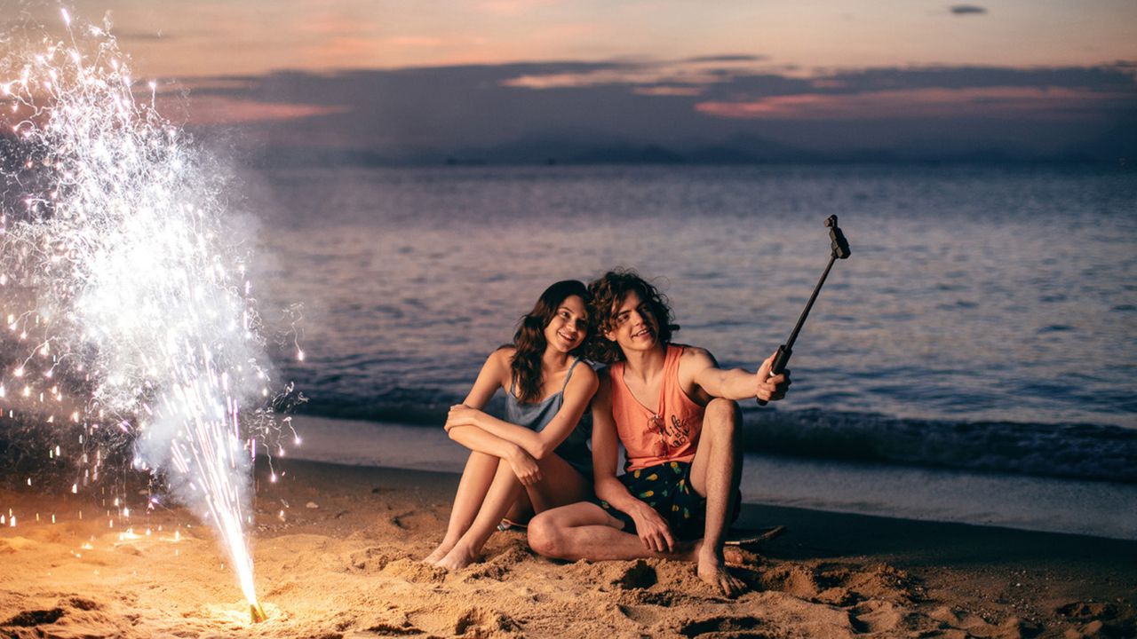 DJI Osmo Pocket Handheld camera used by a couple to take a selfie on a beach at night