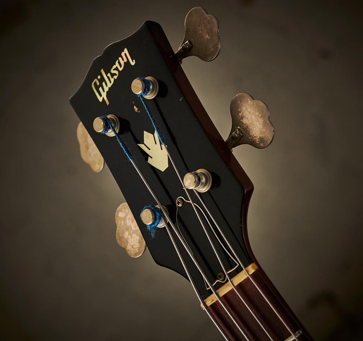 This EB-2 headstock shows a pearl logo and crown inlays, nickel-plated tuners, a laminated plastic &lsquo;bell&rsquo; truss rod cover, and a black nitrocellulose finish over a holly veneer.