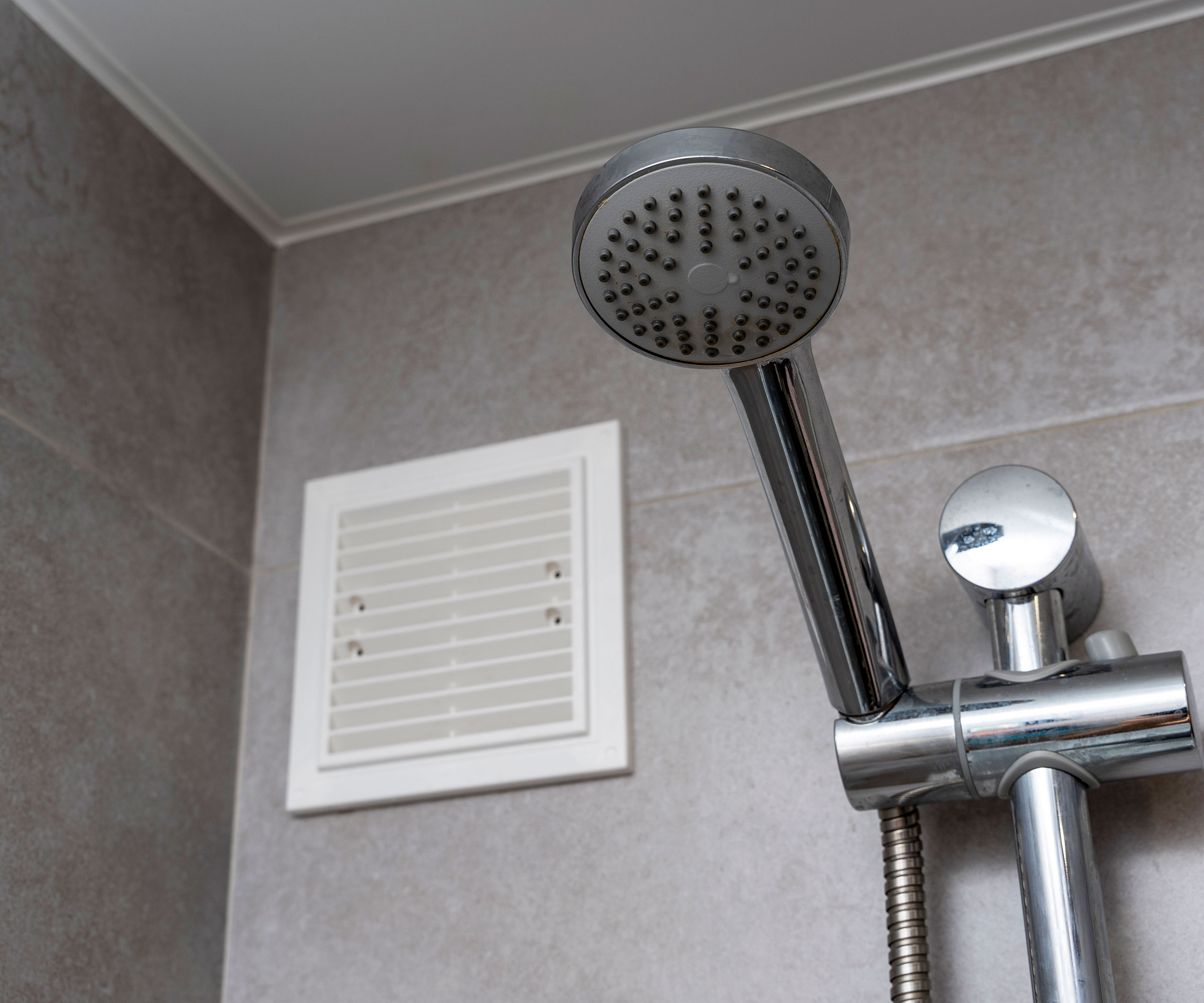 white extractor fan next to chrome handheld shower