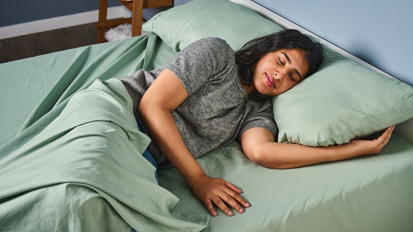 A woman lies on a mattress made up with the Utopia Bedding Sheet Set in a pale green color