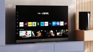 Loewe TV on a pale blue media unit with a black PS5