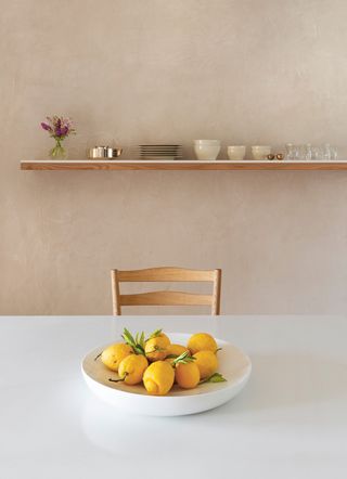 chair at a minimalist dining table with a bowl of lemons