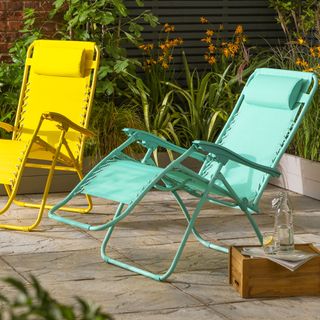 Argos sun loungers in bright colours in a paved garden