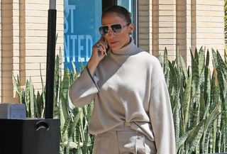 J.Lo wears a gray turtleneck sweater and oversize aviator sunglasses.