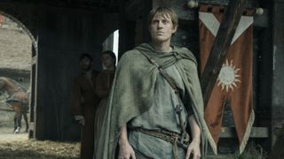 Ser Duncan the Tall standing near a tent with a banner hanging from it in A Knight of the Seven Kingdoms episode 2