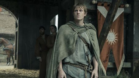 Ser Duncan the Tall standing near a tent with a banner hanging from it in A Knight of the Seven Kingdoms episode 2