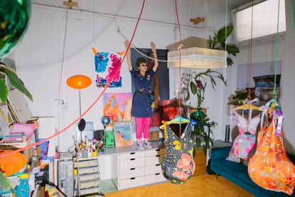 The artist in her studio with some of her video installations and illuminated sculptures made with hangers, lamp shades and swimsuits