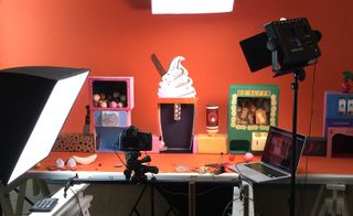 View of a Papermeal video set featuring props relating to ice cream, whipped cream and nuts. Lighting, a camera and a laptop can also be seen