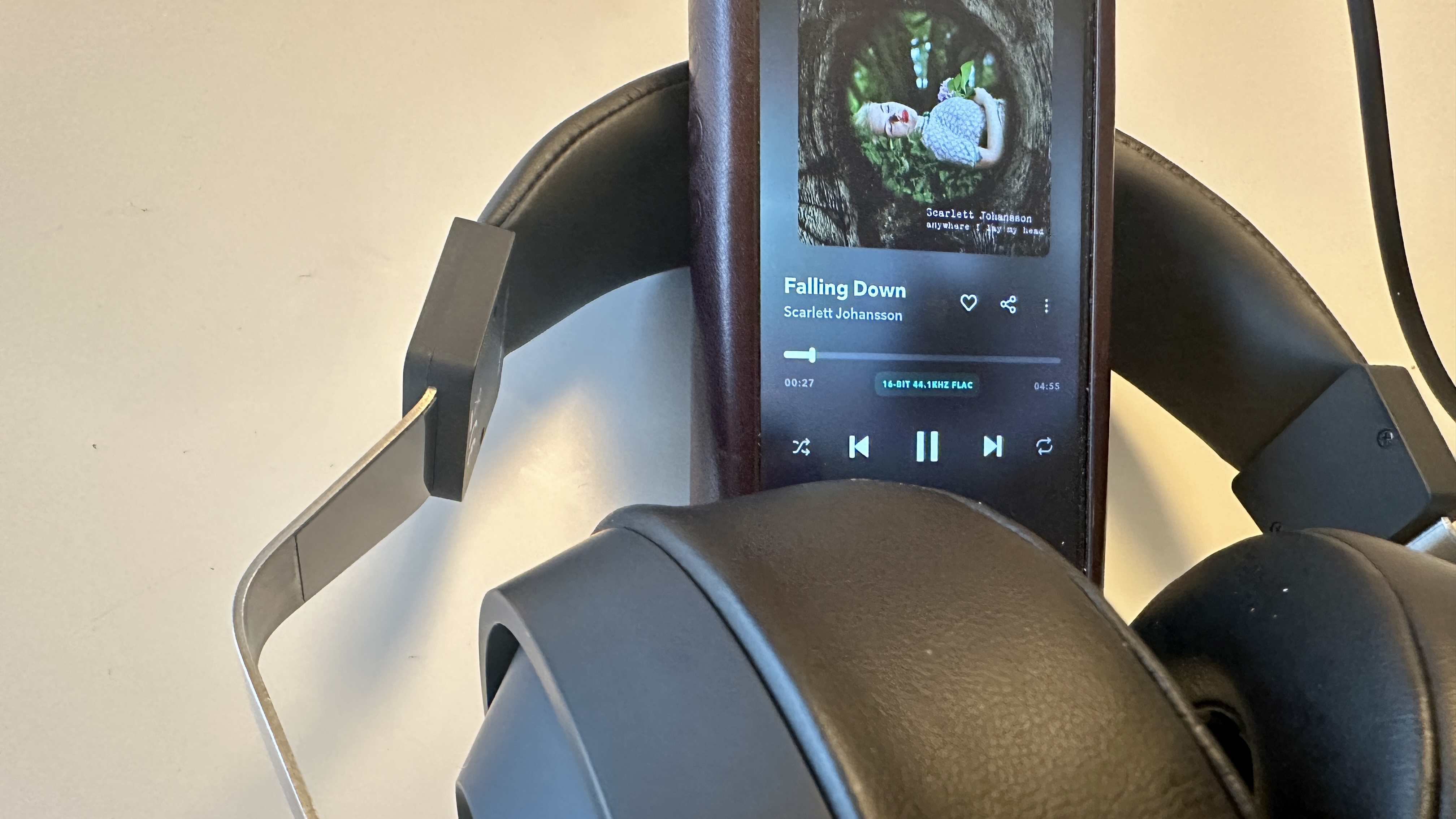 Close ups of the Final DX3000CL with a hi-res digital audio player, showing the ear cups, arm and screen on the player, all on beige background